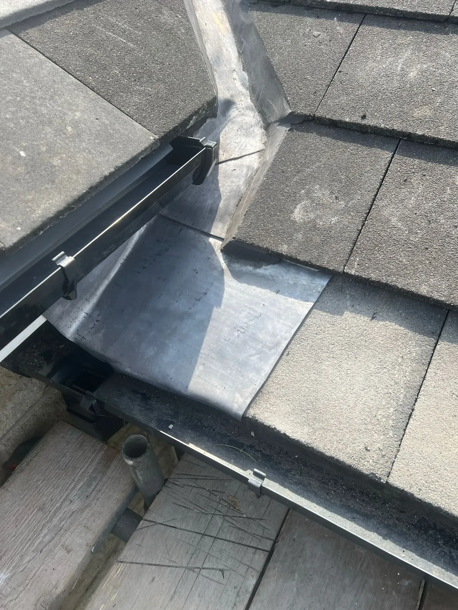 Close-up of roof tiles, lead flashing in a valley, and guttering