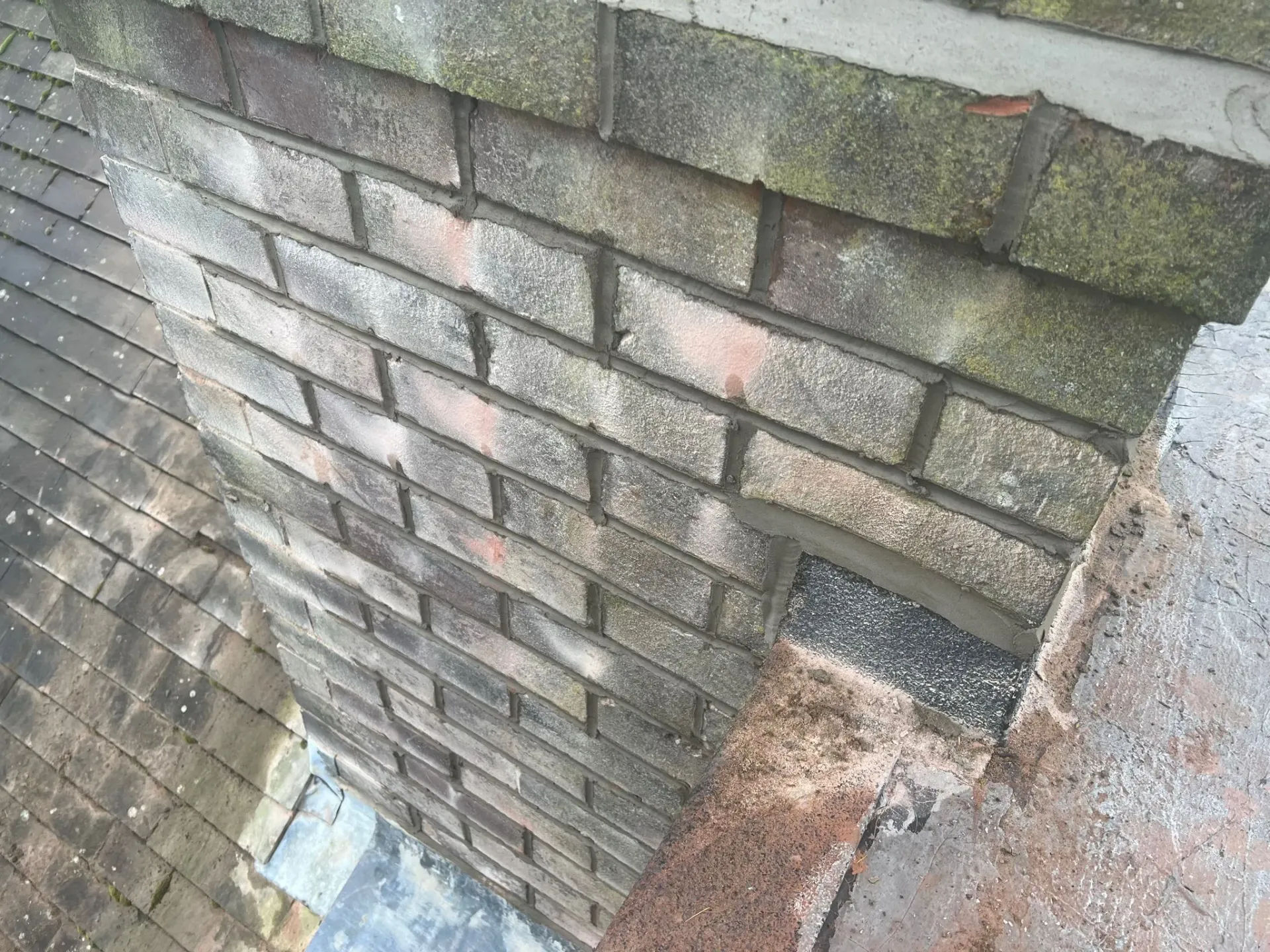 Close up of brick chimney stack and lead flashing on a pitched roof, illustrating chimney repair needs in Sheffield or the Peak District.
