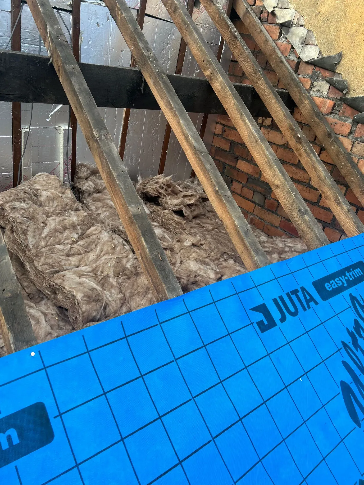 Roof insulation and underlayment being installed within a pitched roof structure in Sheffield or the Peak District.