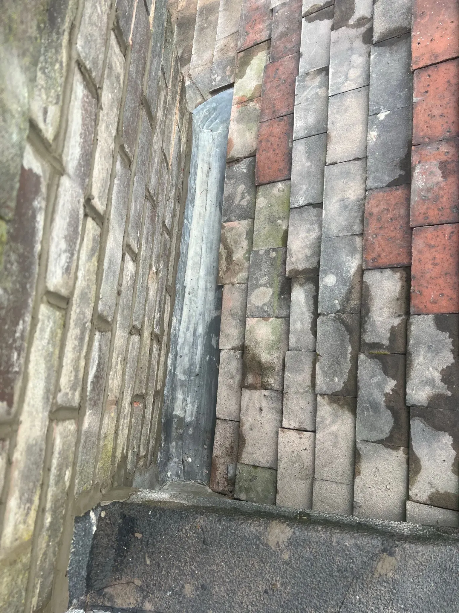 Close up of lead flashing between roof tiles and brickwork on a roof