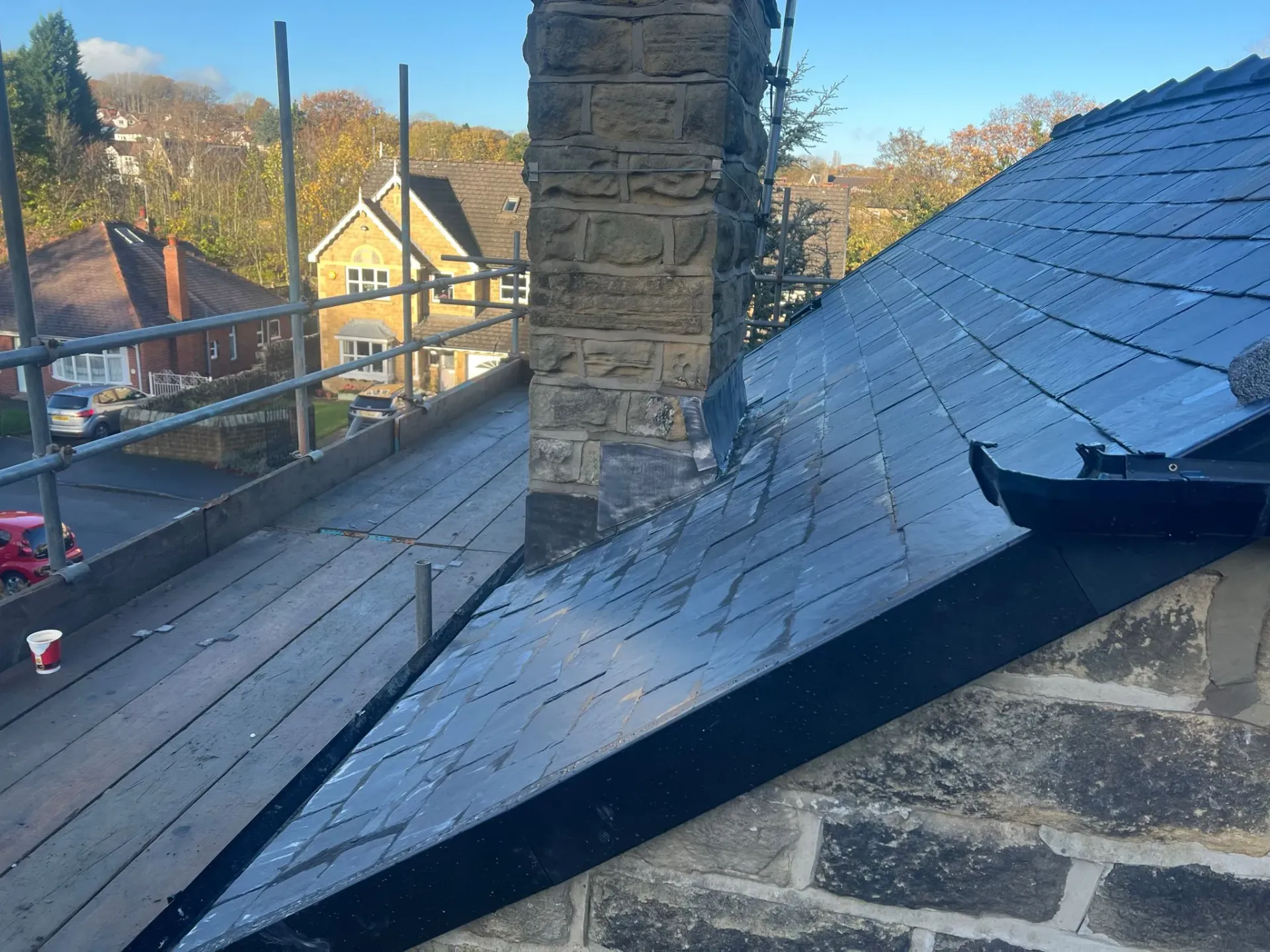 Professional installation or repair of a pitched slate roof with scaffolding and chimney work in Sheffield or the Peak District.