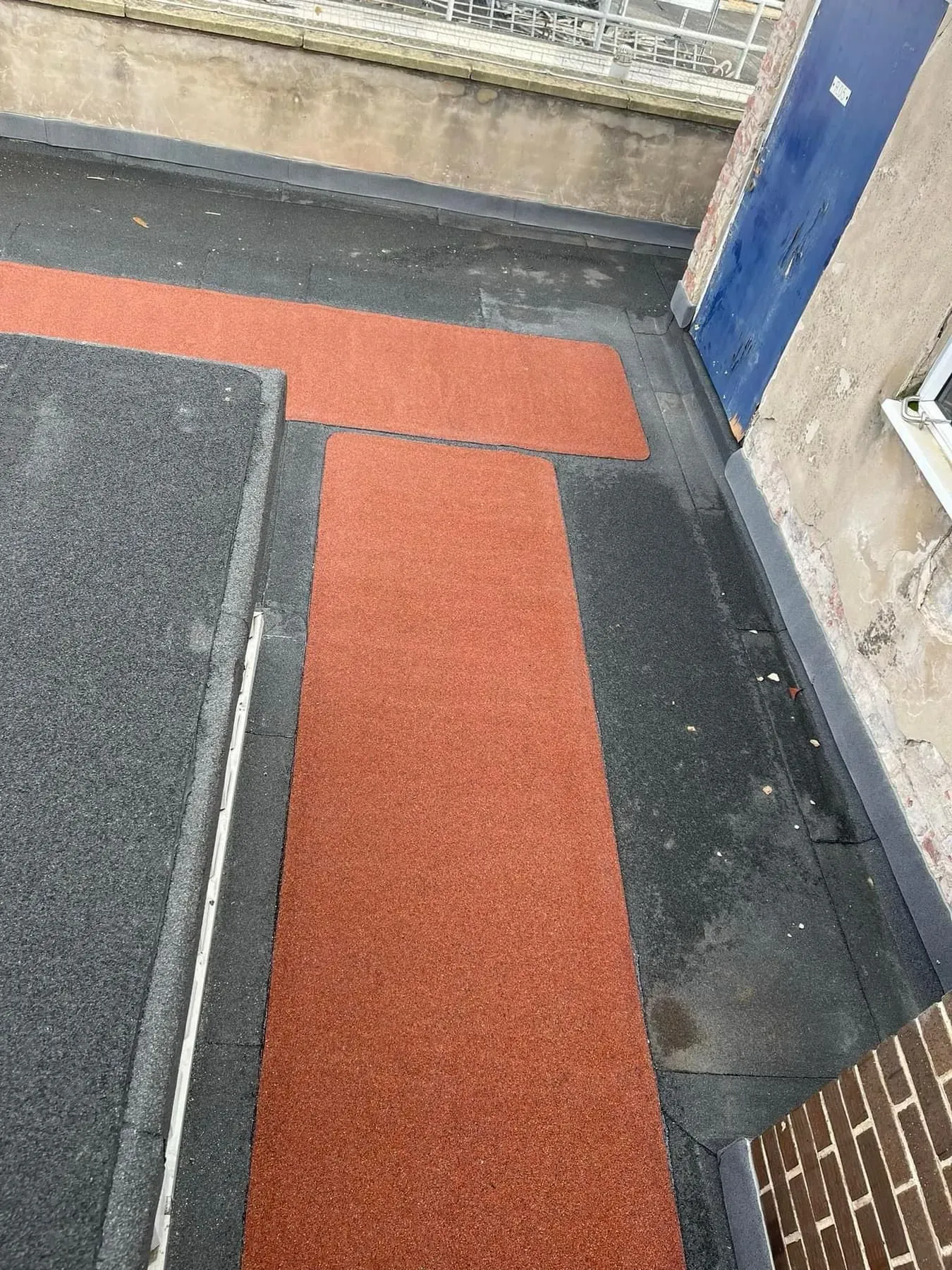 Flat roof with grey and red granulated roofing materials.