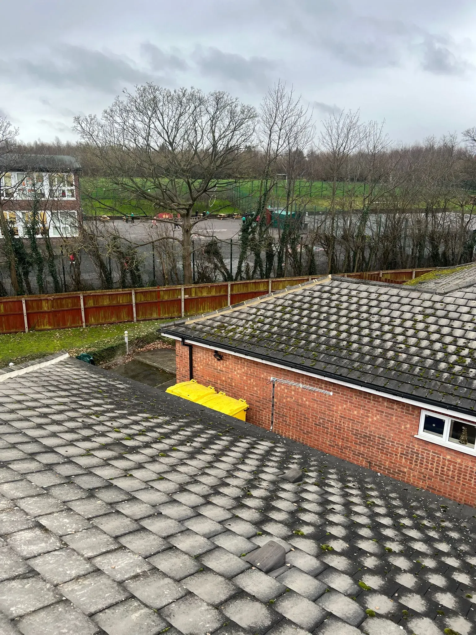 Pitched tiled roofs showing moss and a loose tile in Sheffield or Peak District