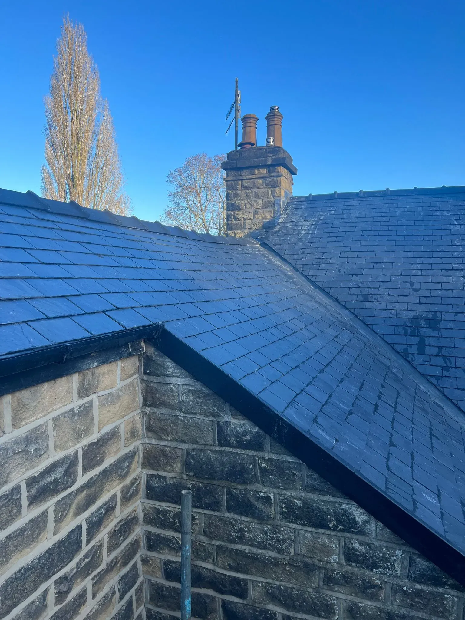 Pitched roof with grey slates, stone chimney and wall - Expert roofing in Sheffield and the Peak District