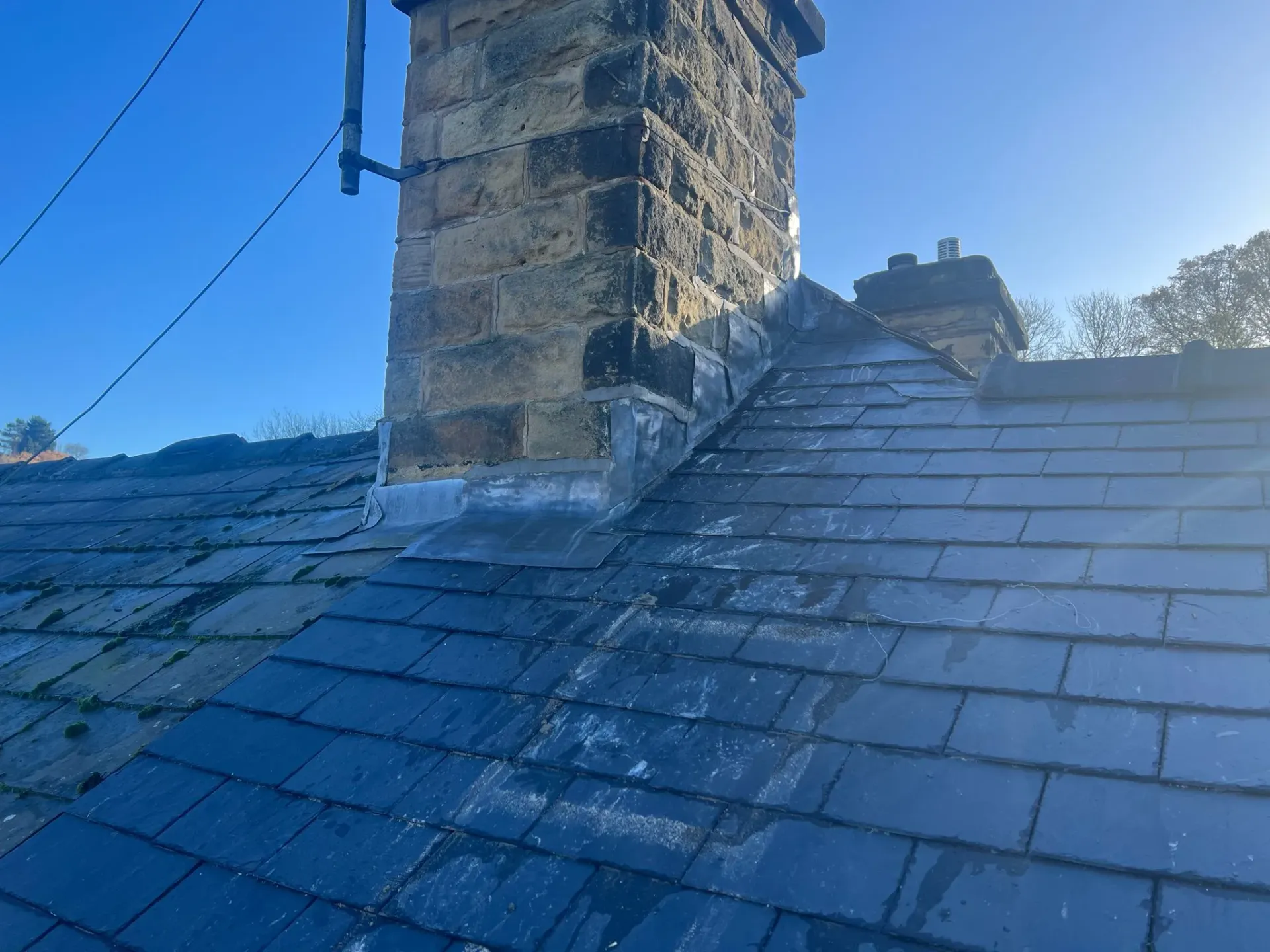 Expert lead flashing around a stone chimney on a slate roof in Sheffield or the Peak District.