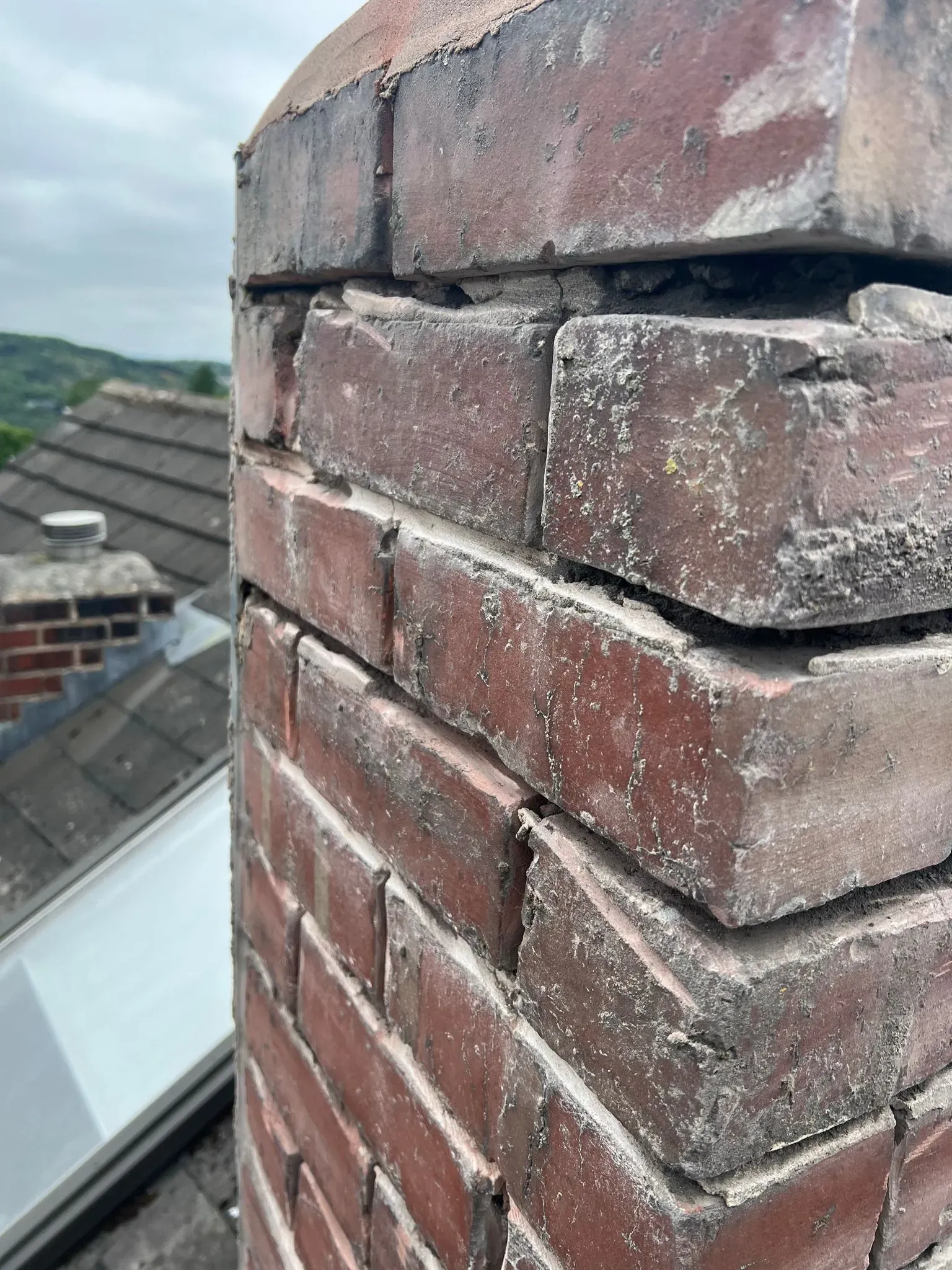 Close-up of a brick chimney on a roof showing crumbling mortar, typical of chimney repair needs in Sheffield or the Peak District.