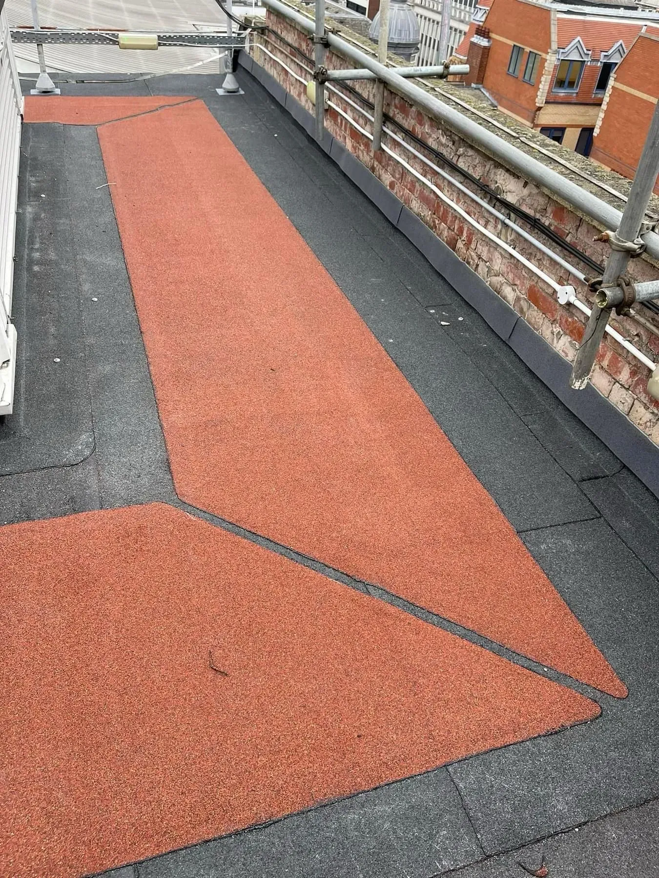 A picture of a flat roof with a red granulated access path or walkway.