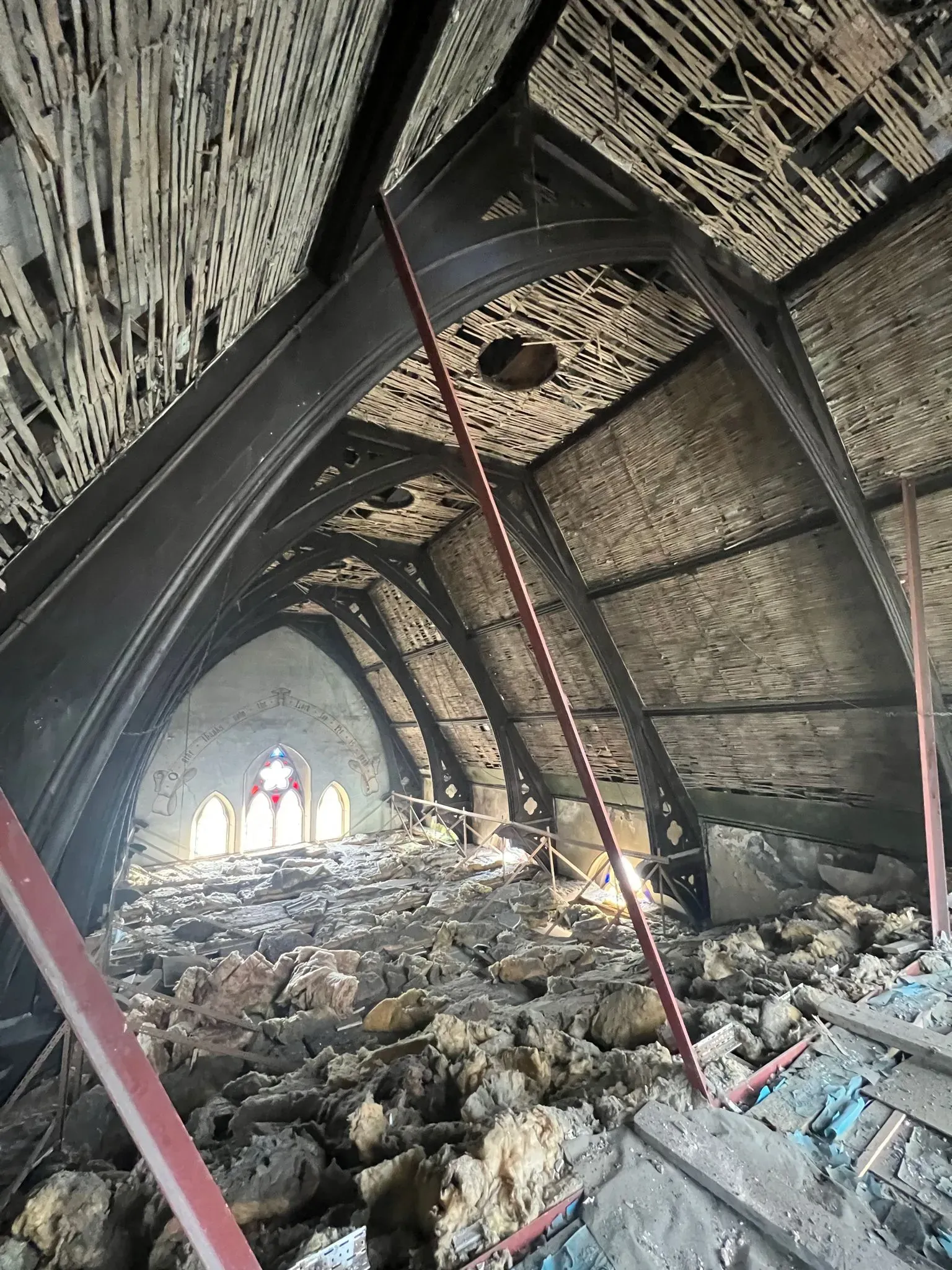 Damaged roof structure interior view showing debris and exposed timbers