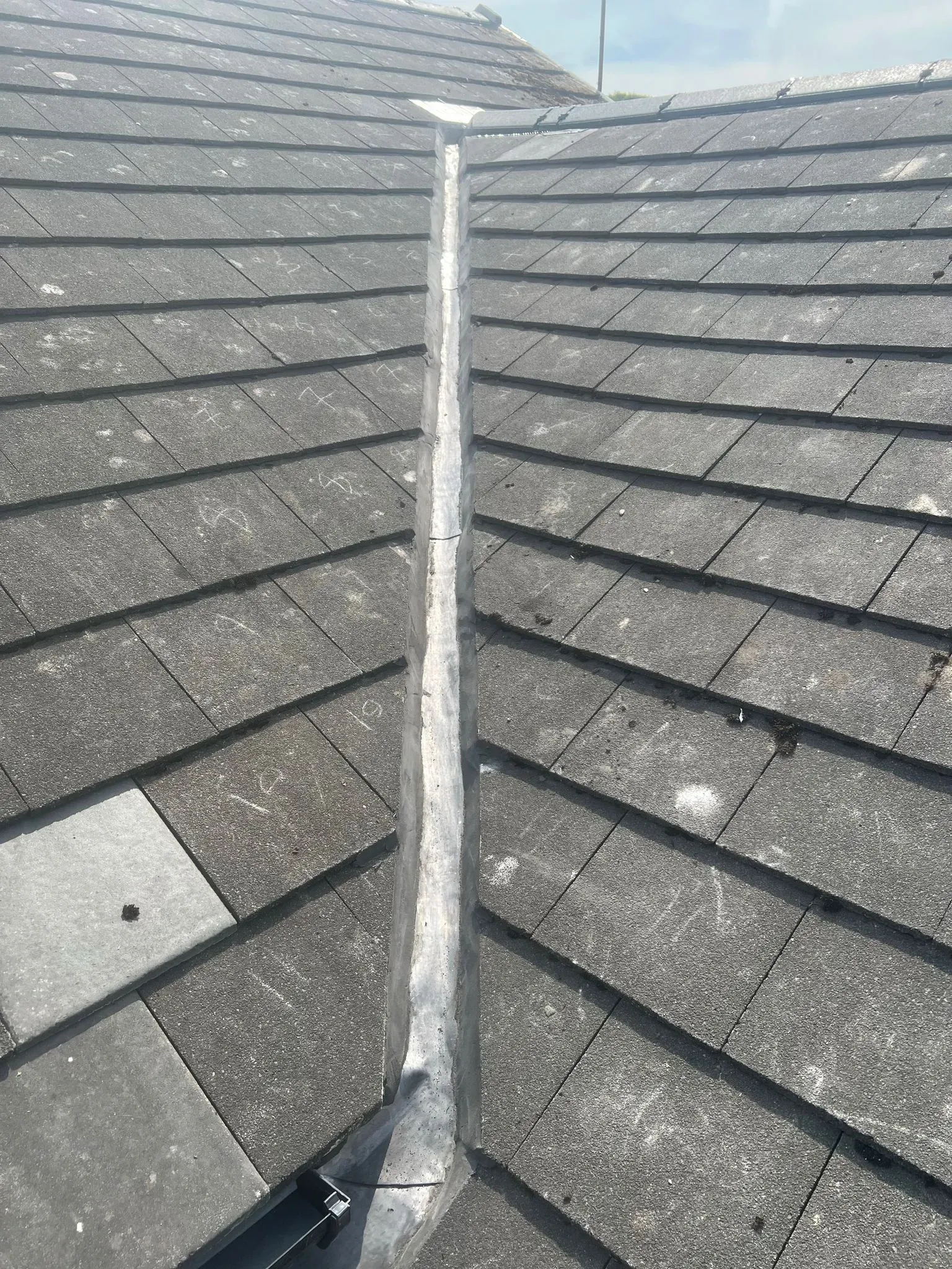 Grey tiled pitched roof with lead valley