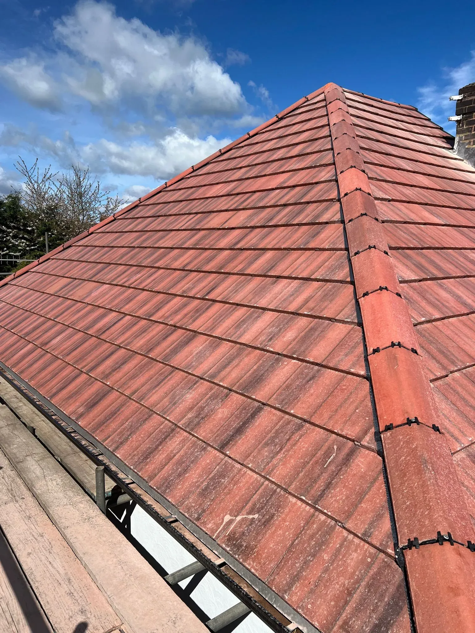 New red roof tiles on a pitched roof with scaffolding