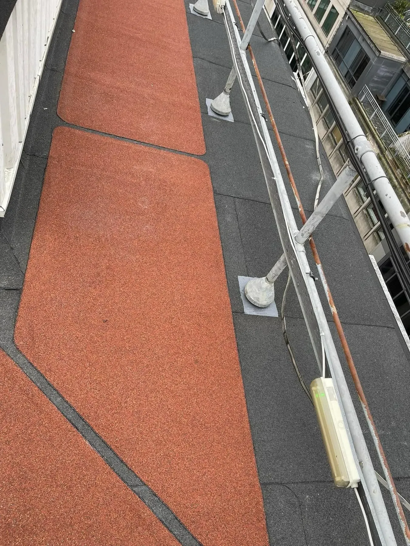 Close-up of a flat roof with red walking pads and metal framework